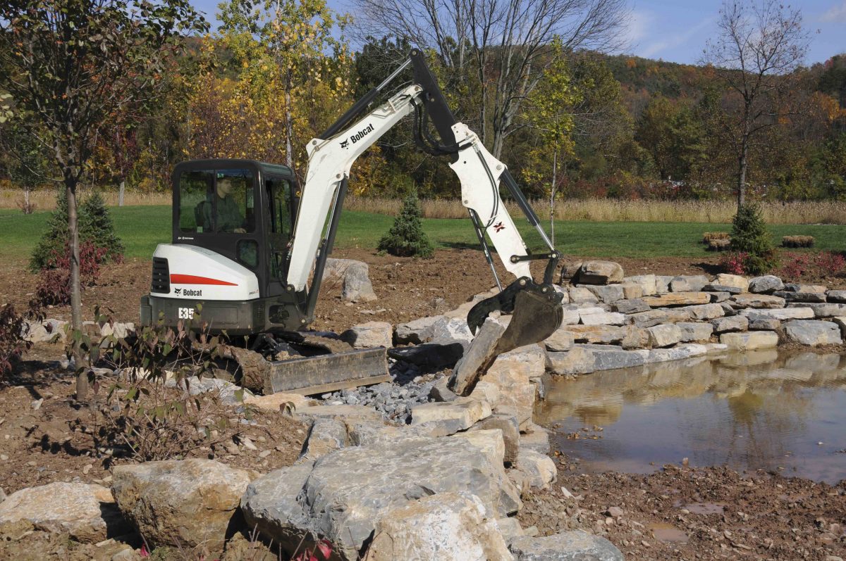 a white and black bulldozer digging rocks in a field.