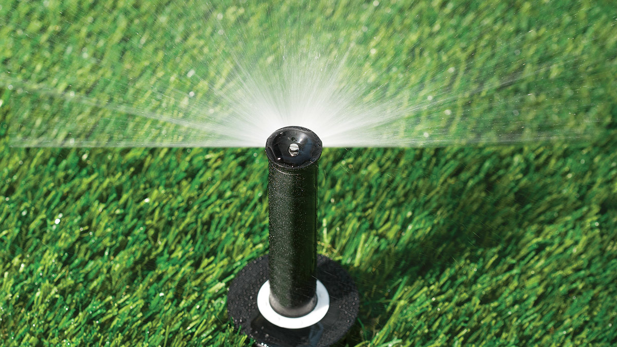 a sprinkler spraying water on a green lawn.