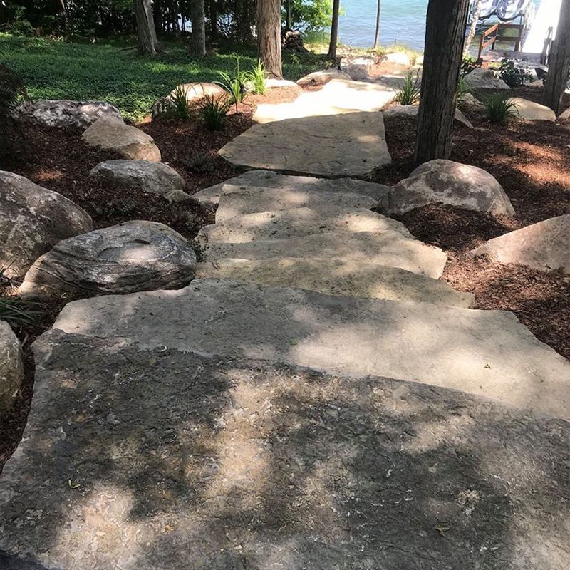 a stone path in the middle of a park.