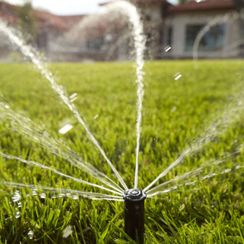 a sprinkler spraying water on a green lawn.