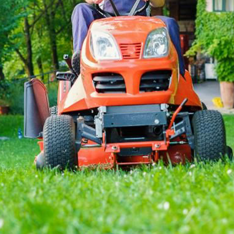 a man riding on the back of a red lawn mower.
